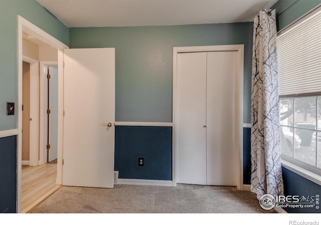 unfurnished bedroom featuring light colored carpet and a closet