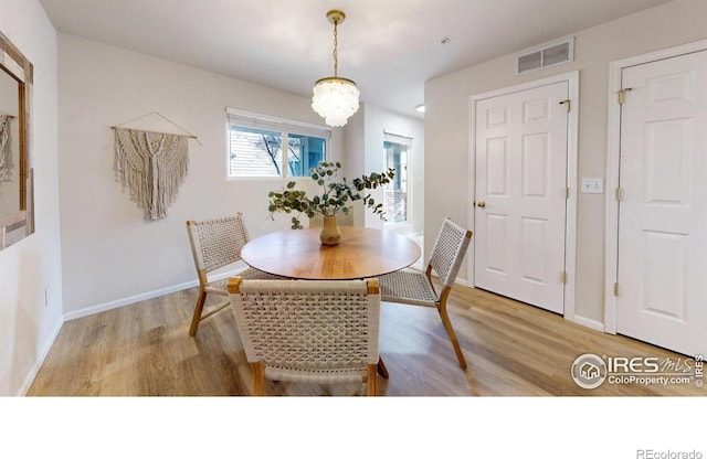 dining space featuring light hardwood / wood-style floors and a chandelier