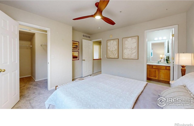 bedroom featuring ensuite bath, ceiling fan, a walk in closet, light colored carpet, and a closet