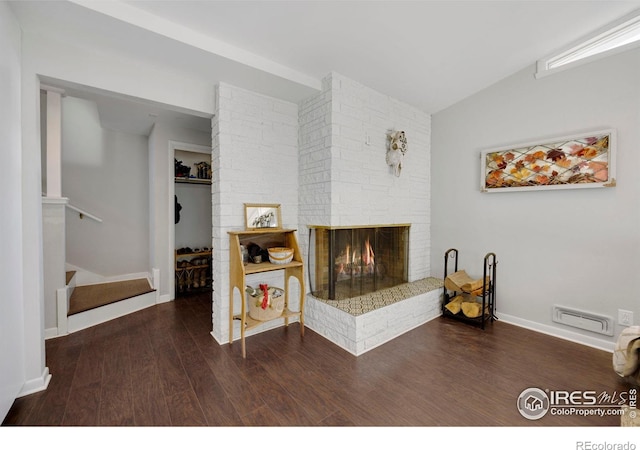 living room featuring lofted ceiling, dark hardwood / wood-style floors, and a brick fireplace