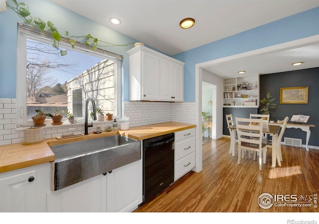 kitchen featuring wooden counters, built in shelves, sink, white cabinets, and black dishwasher