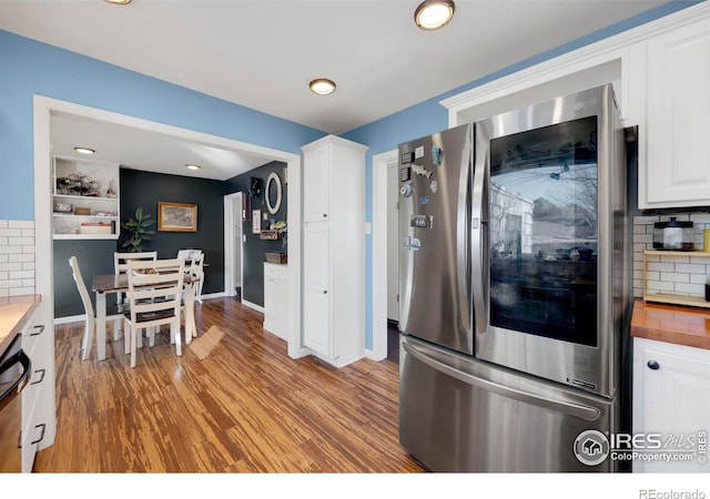 kitchen with stainless steel fridge, backsplash, butcher block countertops, white cabinets, and light hardwood / wood-style floors