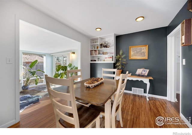 dining area with built in shelves and dark hardwood / wood-style floors