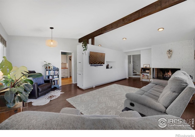 living room with beamed ceiling, dark hardwood / wood-style floors, and a brick fireplace