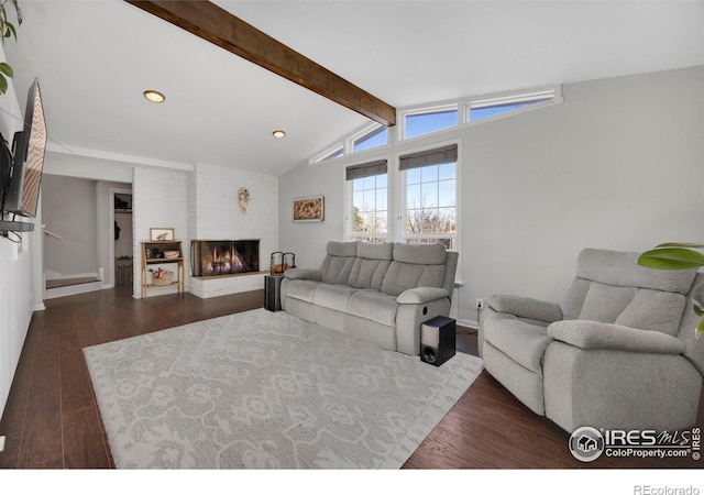 living room featuring vaulted ceiling with beams, dark wood-type flooring, and a brick fireplace