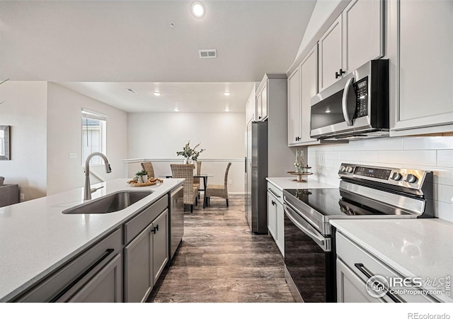 kitchen with appliances with stainless steel finishes, dark hardwood / wood-style flooring, tasteful backsplash, gray cabinetry, and sink