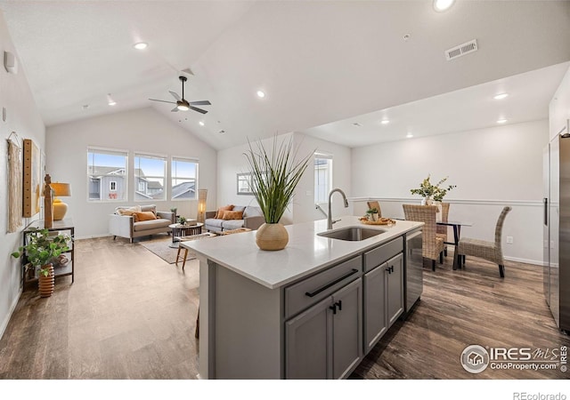 kitchen with dishwasher, sink, an island with sink, vaulted ceiling, and gray cabinets