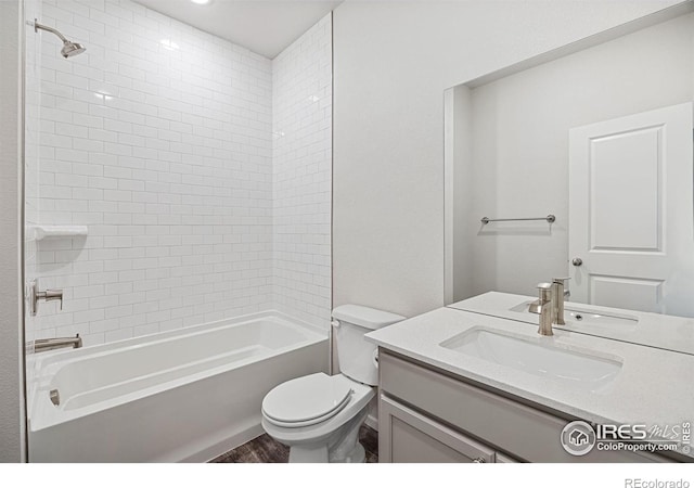 full bathroom featuring vanity, tiled shower / bath combo, and toilet