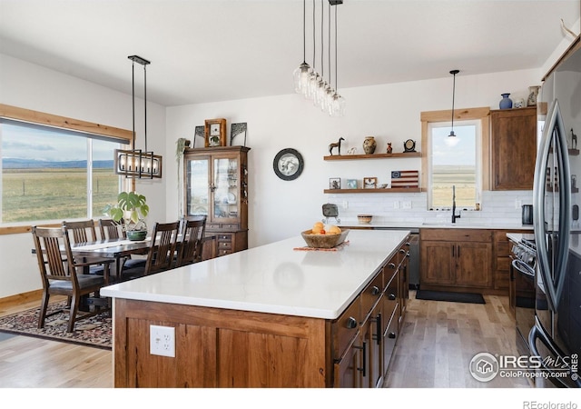 kitchen with a center island, light hardwood / wood-style floors, backsplash, and hanging light fixtures