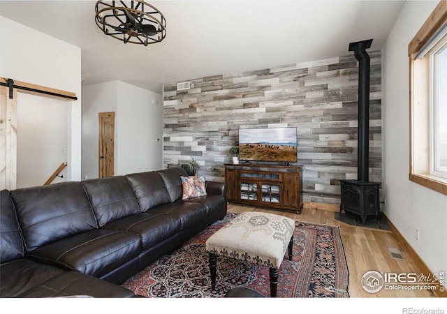 living room with a wood stove, ceiling fan, and wood-type flooring