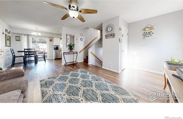 living room featuring a textured ceiling, hardwood / wood-style floors, and ceiling fan with notable chandelier