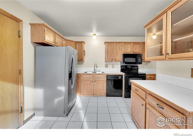 kitchen with sink, light tile patterned floors, and black appliances