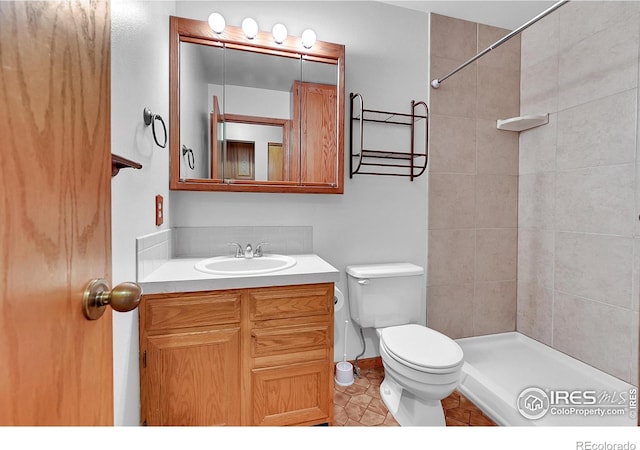 bathroom with tiled shower, vanity, and toilet