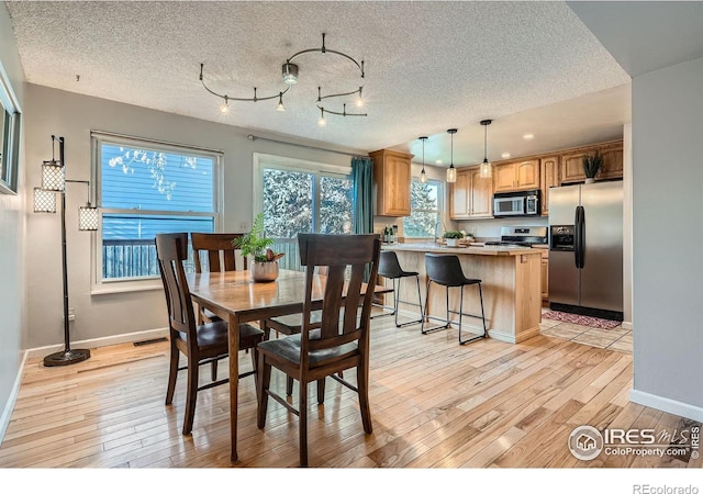 dining area featuring a textured ceiling and light hardwood / wood-style floors