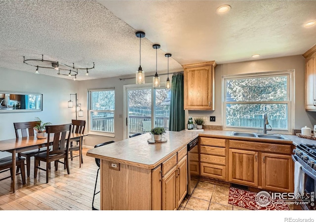 kitchen featuring sink, rail lighting, a textured ceiling, decorative light fixtures, and appliances with stainless steel finishes