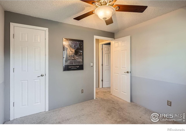 unfurnished bedroom with a textured ceiling, light colored carpet, and ceiling fan