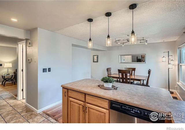 kitchen featuring dishwasher, pendant lighting, rail lighting, and light tile patterned flooring