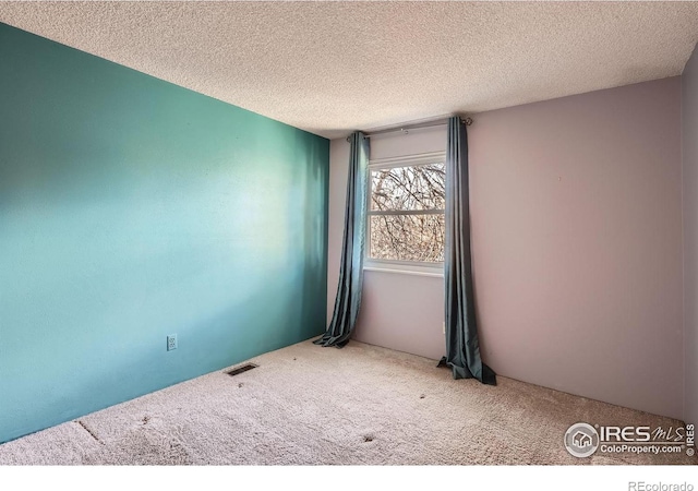 spare room featuring a textured ceiling and carpet floors