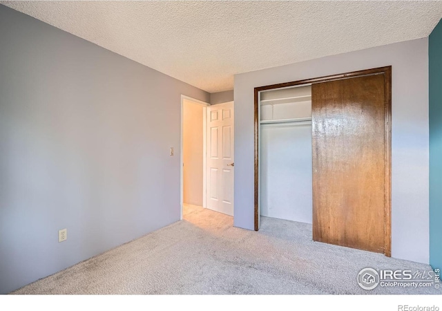 unfurnished bedroom with light carpet, a textured ceiling, and a closet