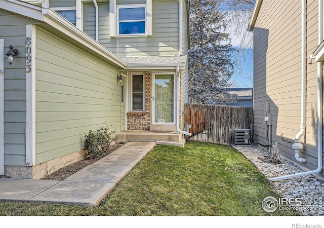 view of exterior entry featuring a yard and central AC