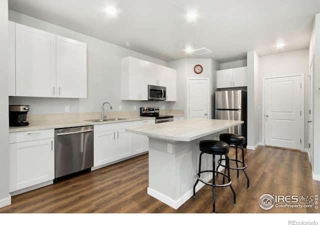 kitchen featuring sink, dark hardwood / wood-style floors, a kitchen island, white cabinetry, and stainless steel appliances