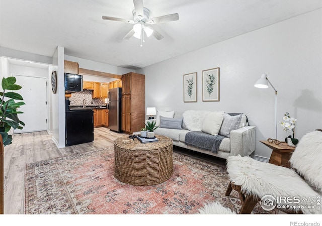 living room with ceiling fan and light hardwood / wood-style flooring