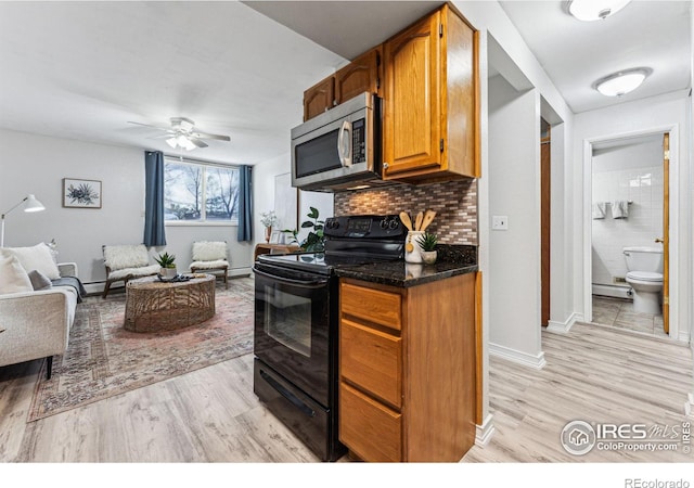 kitchen featuring black range with electric stovetop, ceiling fan, a baseboard heating unit, decorative backsplash, and light wood-type flooring