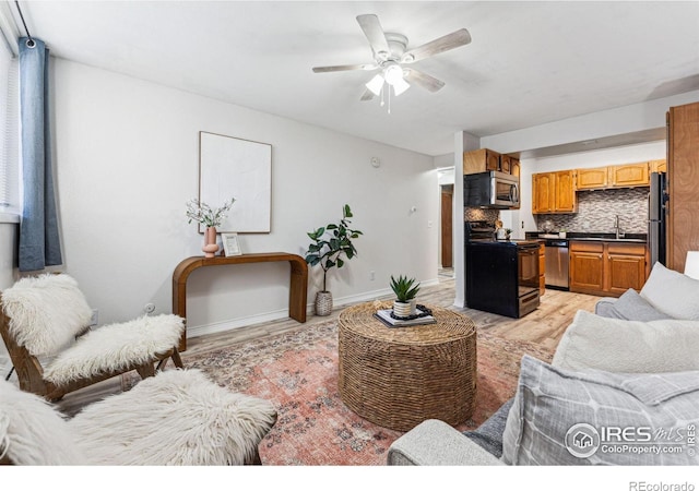 living room with ceiling fan, sink, and light wood-type flooring