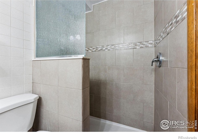 bathroom with a tile shower and toilet