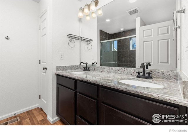 bathroom with vanity, hardwood / wood-style flooring, walk in shower, and a notable chandelier