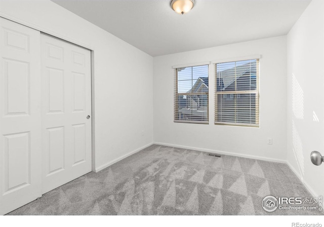 unfurnished bedroom with light colored carpet and a closet