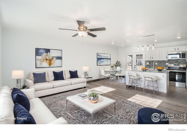 living room featuring ceiling fan and dark wood-type flooring