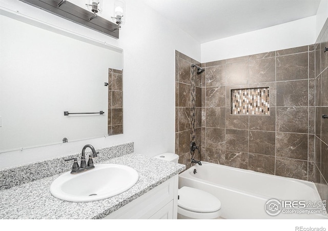 full bathroom featuring toilet, vanity, and tiled shower / bath