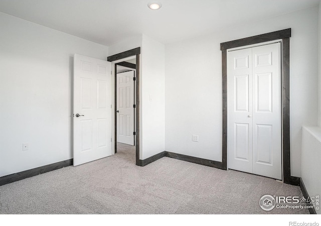 unfurnished bedroom featuring light colored carpet and a closet