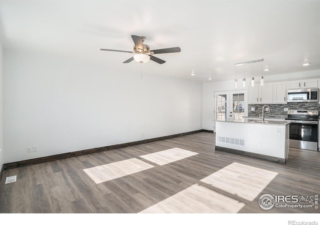 kitchen featuring pendant lighting, ceiling fan, an island with sink, white cabinetry, and stainless steel appliances