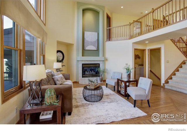 living room featuring a tile fireplace, hardwood / wood-style floors, a high ceiling, and washing machine and dryer