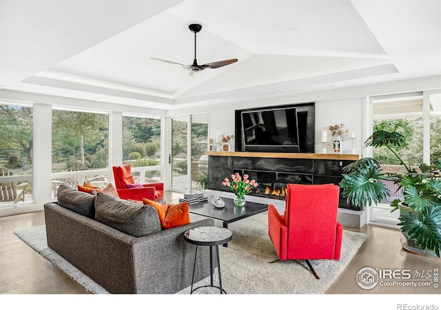 living room featuring a tray ceiling, vaulted ceiling, ceiling fan, and light hardwood / wood-style floors