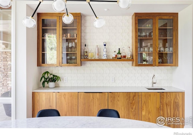 bar featuring decorative backsplash, pendant lighting, and sink