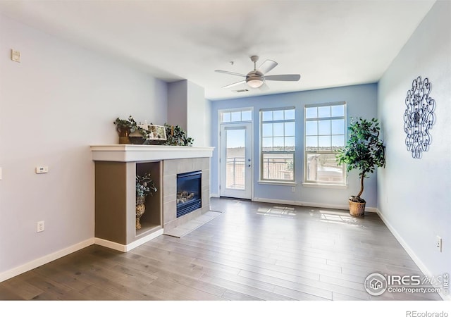 unfurnished living room featuring a fireplace, wood-type flooring, and ceiling fan