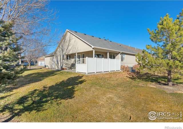 back of property featuring a garage and a yard