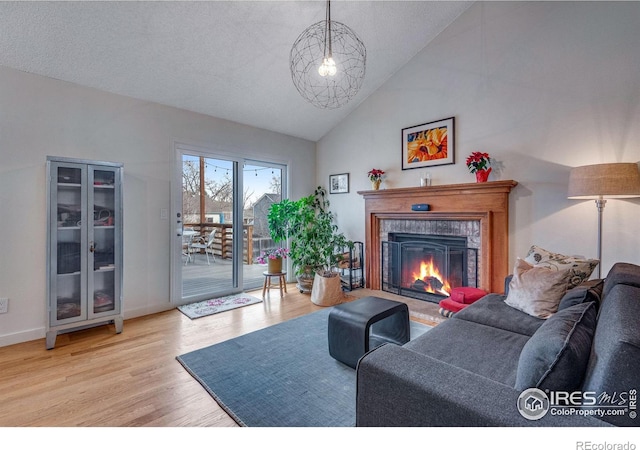 living room with a textured ceiling, high vaulted ceiling, and light hardwood / wood-style flooring