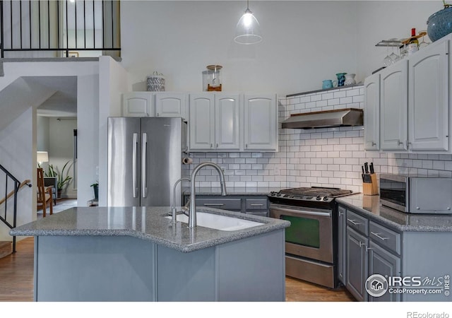 kitchen with appliances with stainless steel finishes, ventilation hood, sink, decorative light fixtures, and gray cabinets