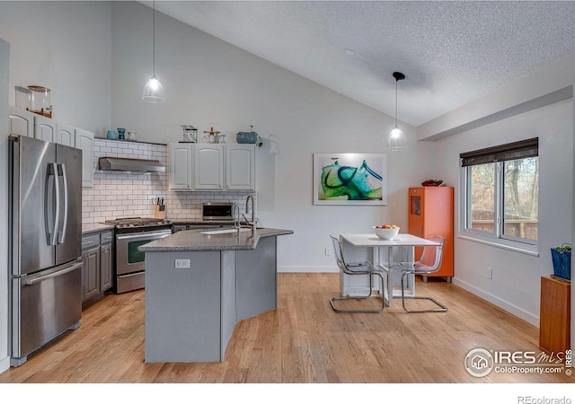 kitchen with a center island with sink, decorative light fixtures, stainless steel appliances, and exhaust hood