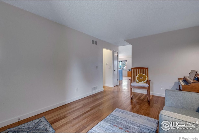 living room with a textured ceiling and light hardwood / wood-style floors