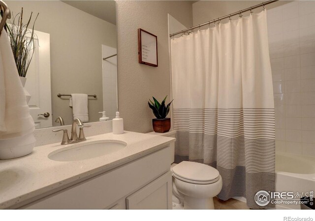 full bathroom featuring toilet, shower / bathtub combination with curtain, and vanity