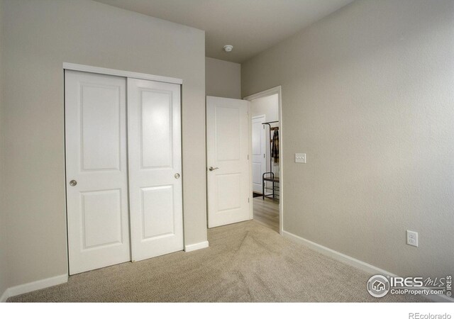 unfurnished bedroom with light colored carpet and a closet