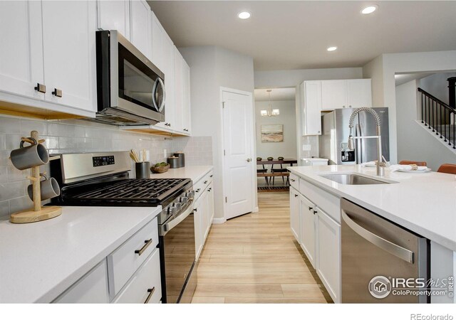 kitchen with white cabinetry, stainless steel appliances, tasteful backsplash, light hardwood / wood-style flooring, and sink