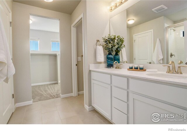 bathroom with a shower with door, vanity, and tile patterned flooring