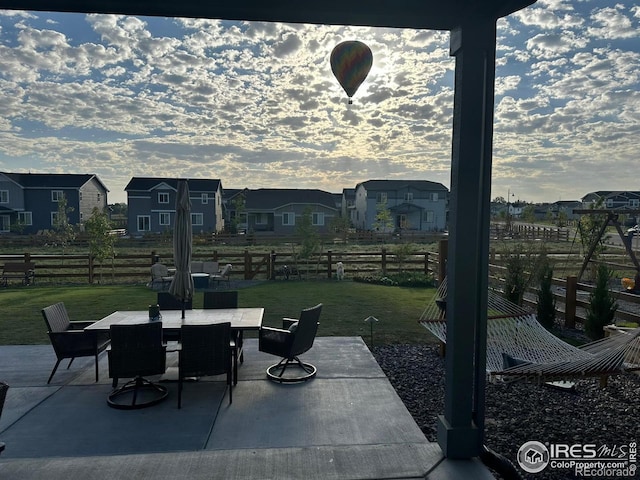 patio terrace at dusk featuring a lawn