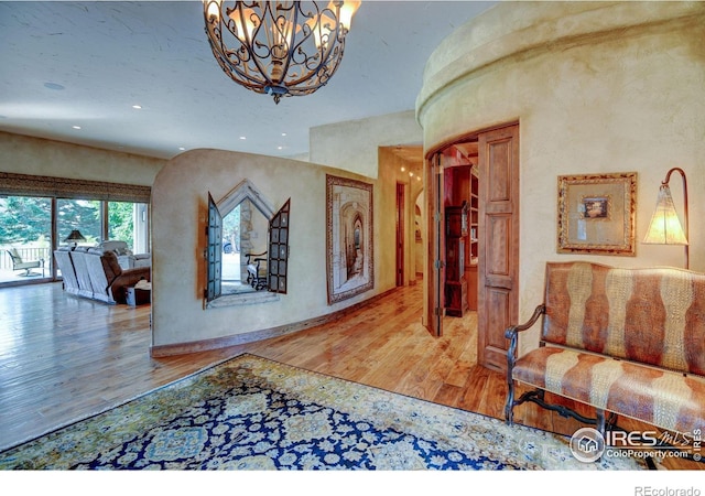 corridor with a notable chandelier and hardwood / wood-style flooring